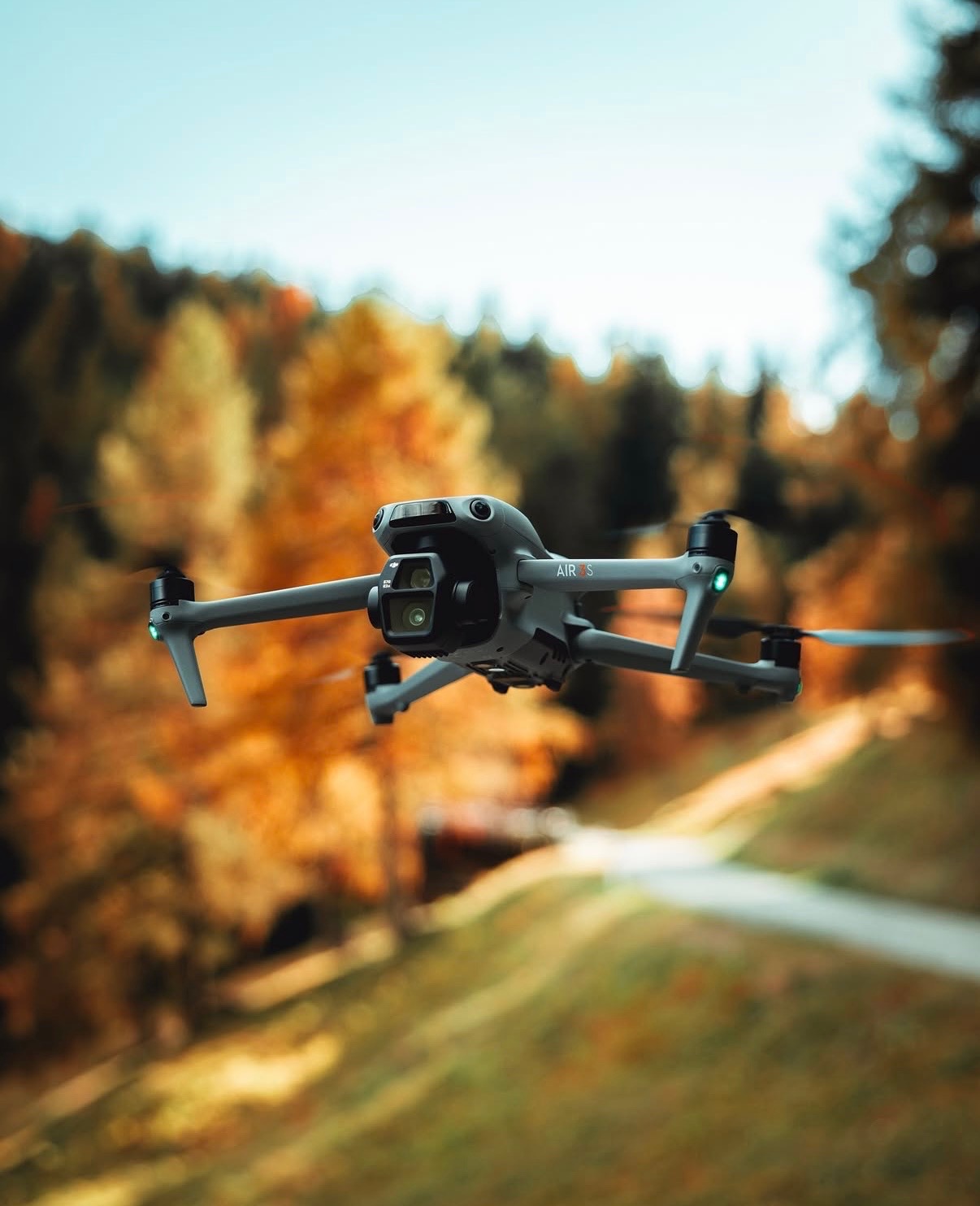 DJI Air 3S drone in flight over autumn forest