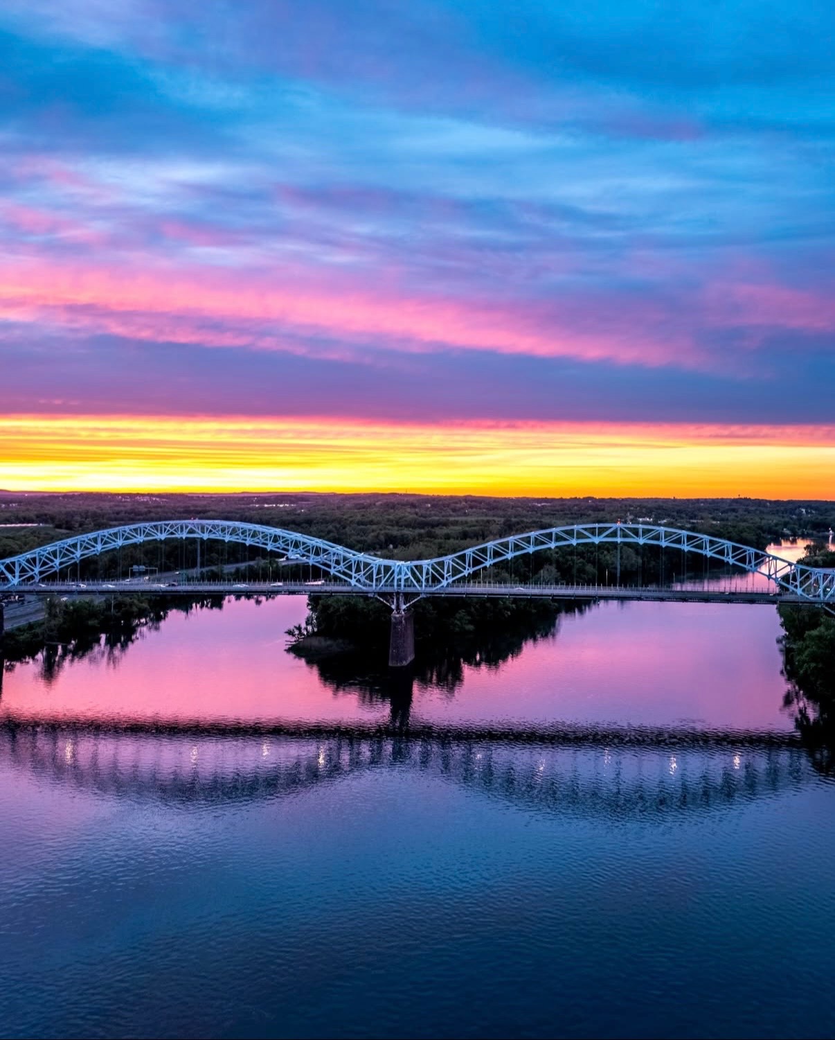 Aerial view of a riverfront bridge at dusk